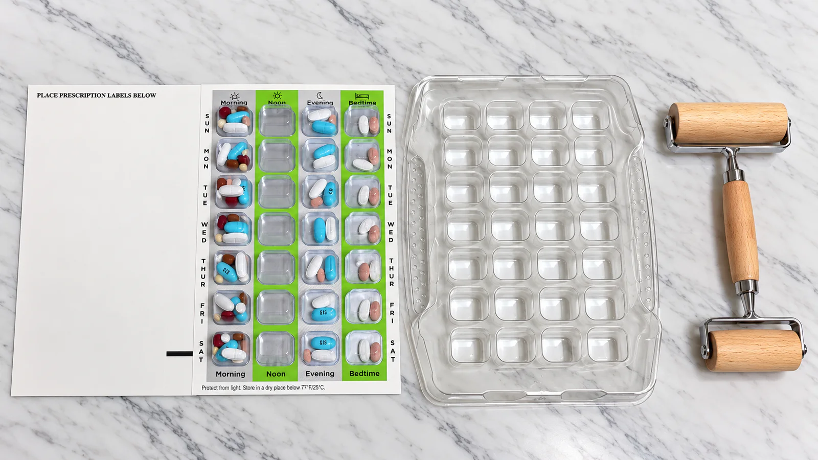 Weekly medication blister card beside the clear sealing tray and packaging rollers